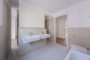 Masterbad mit Doppelwaschtisch und Badewanne – die Rainshower-Dusche liegt diskret hinter der Trennwand und schafft einen angenehm separierten Duschbereich